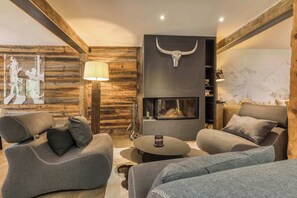 A cozy living room with a fireplace, wooden walls, and modern furniture.