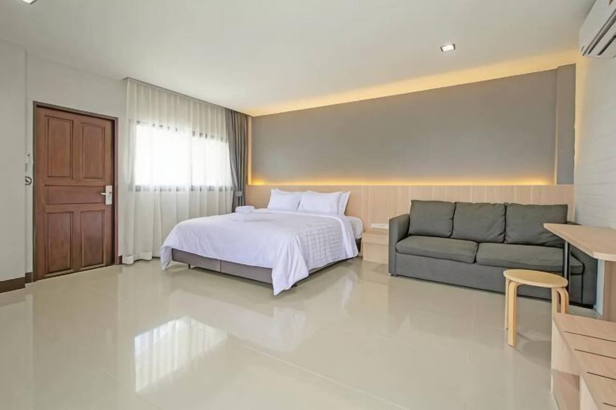 A modern hotel room with a bed, sofa, and a small table.