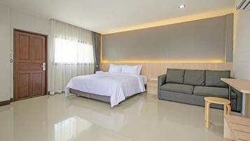 Quarto de hotel moderno com cama, sofá e uma pequena mesa.