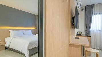 Quarto de hotel moderno com cama, mesa de cabeceira, luminária e vista para a cidade.