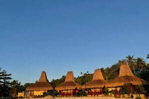 A row of thatched-roof huts with a clear sky. - Three Queen Villa and Homestay (Wanokaka)