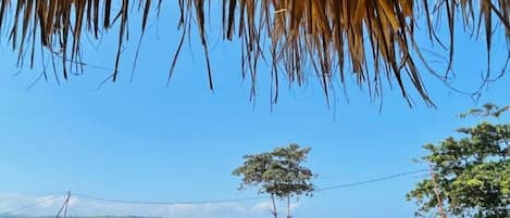 A beach view with a stone wall, a thatched roof, and a clear blue sky.
