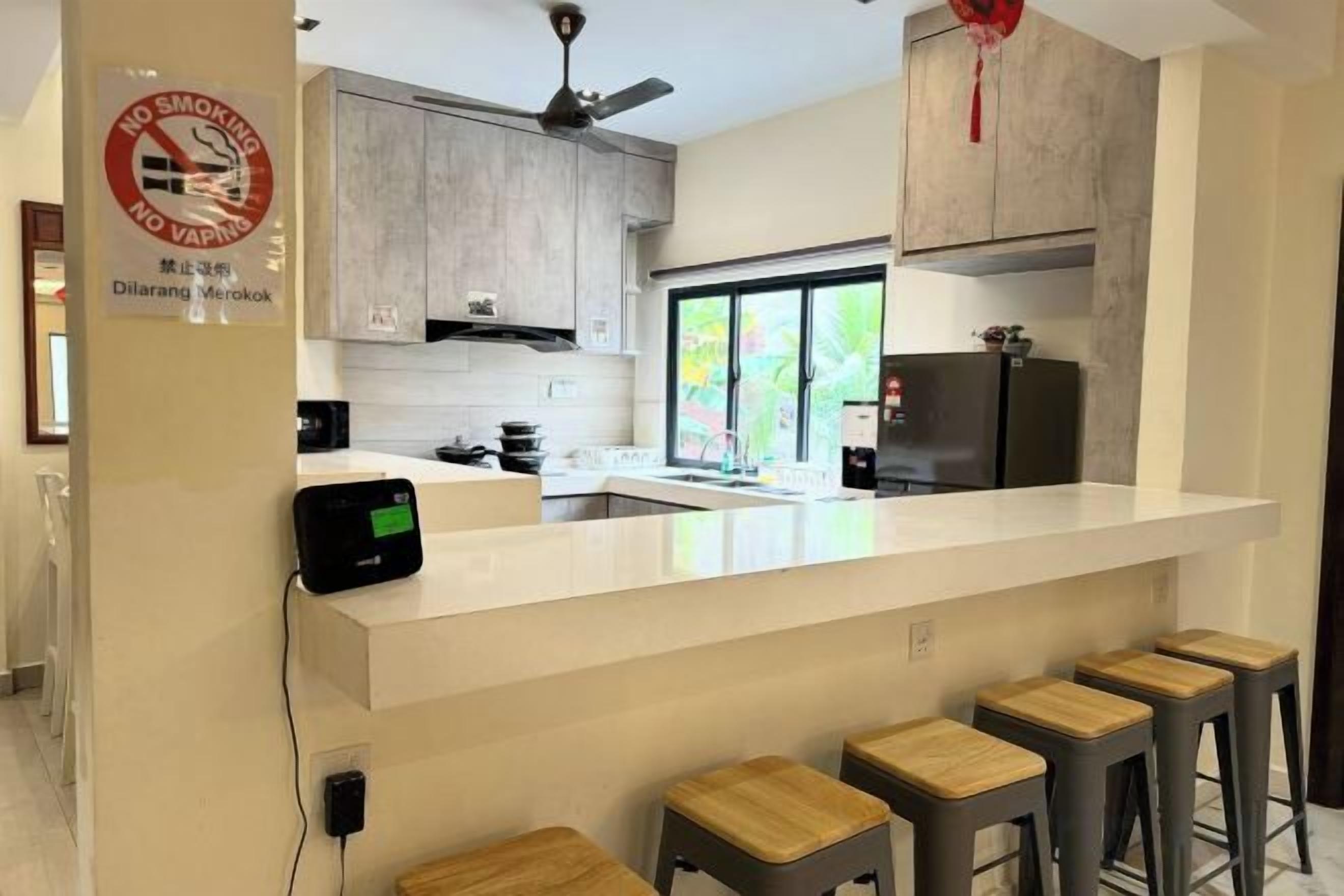 Una cocina moderna con una isla central, taburetes de bar y un cartel de prohibido fumar.
