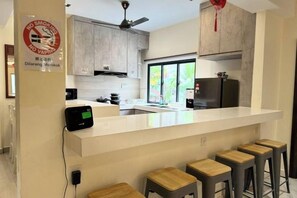 Una cocina moderna con una isla central, taburetes de bar y un cartel de prohibido fumar.