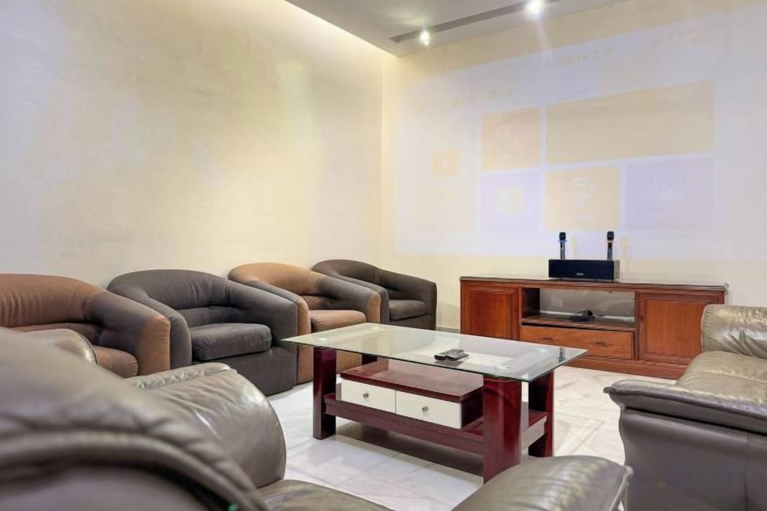 A living room with leather sofas, a glass coffee table, and a wooden cabinet.
