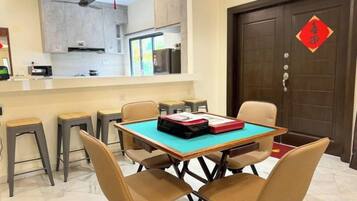 Un comedor con una mesa y sillas, una cocina al fondo, y una puerta tradicional con un detalle rojo.