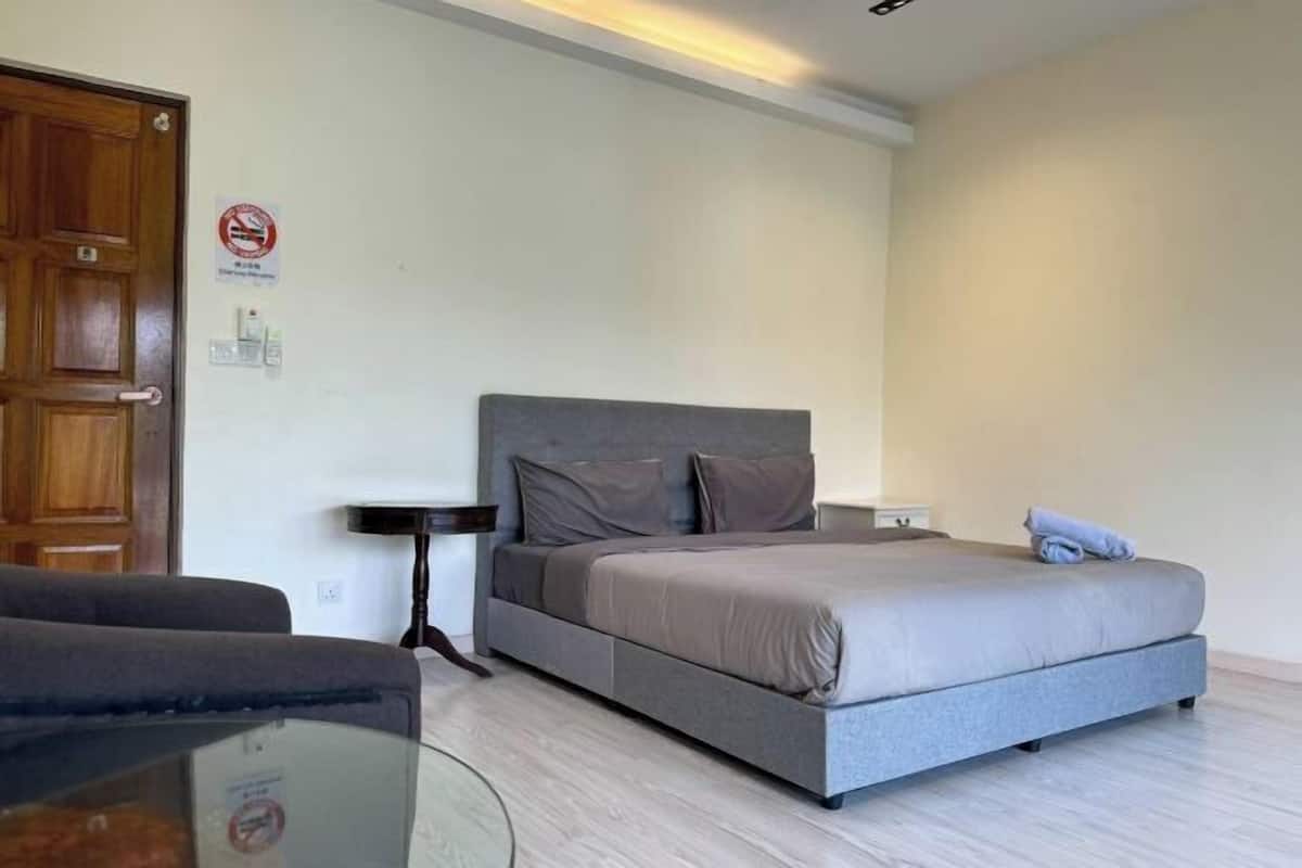 Ein Schlafzimmer mit einem Bett, einem Nachttisch, einem Sessel und einer Tür.