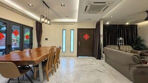 A modern living room with a dining area, featuring a wooden dining table, comfortable seating, a sofa, and a large window with curtains. - Gathering l Wedding House l 18PaxTaman Oug KL (Kuala Lumpur)