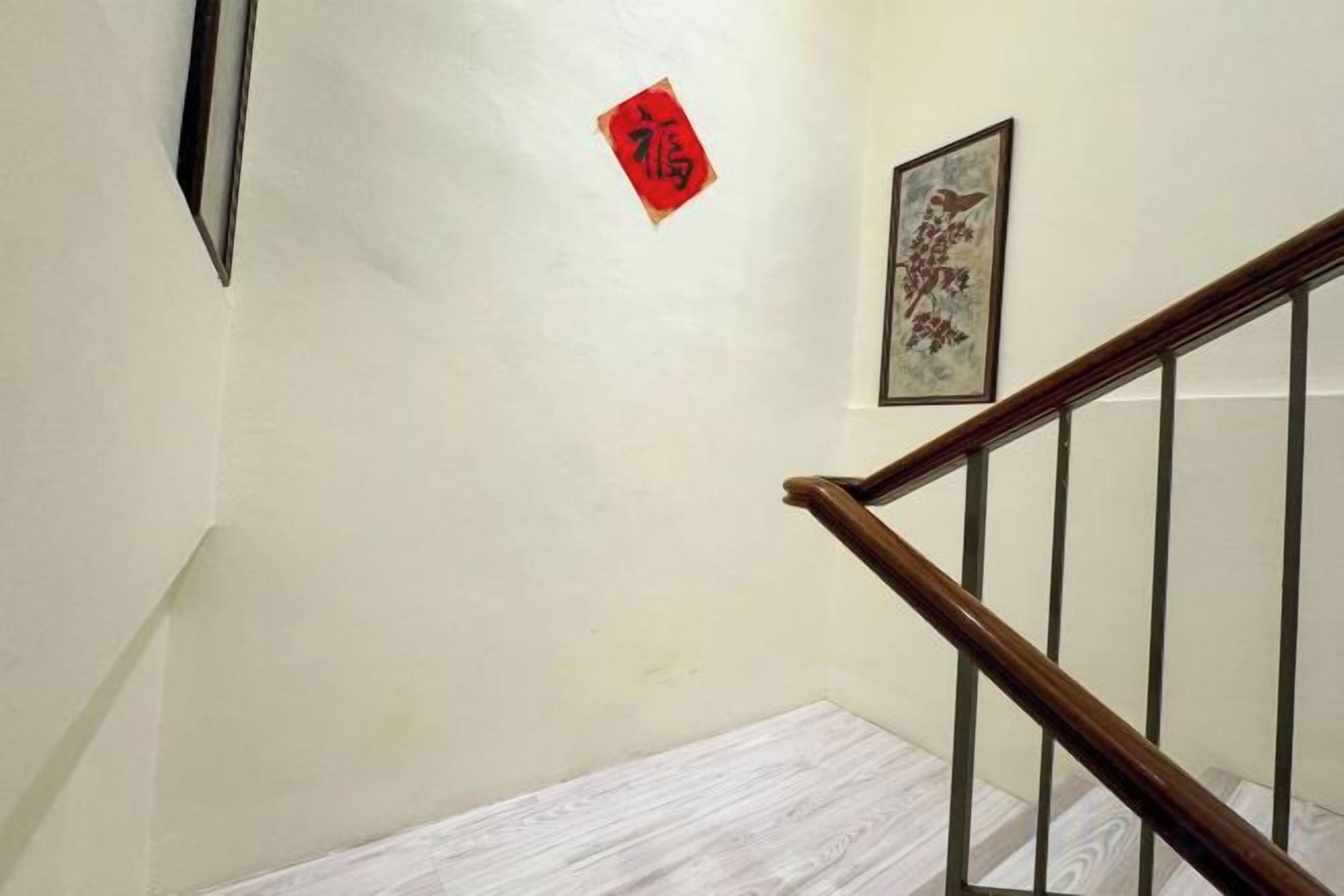 Una escalera con barandilla de madera y pared blanca.