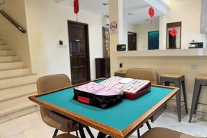 Una habitación con una mesa preparada para un juego, una escalera y una zona de cocina al fondo.