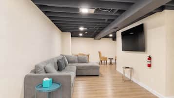 Una sala moderna con un sofá modular, una mesita redonda y un televisor de pantalla plana montado en la pared.