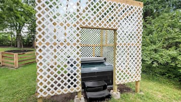 A wooden deck with a white lattice fence, a hot tub, and a small black bench.
