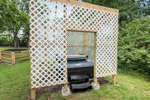 A wooden deck with a white lattice fence, a hot tub, and a small black bench.