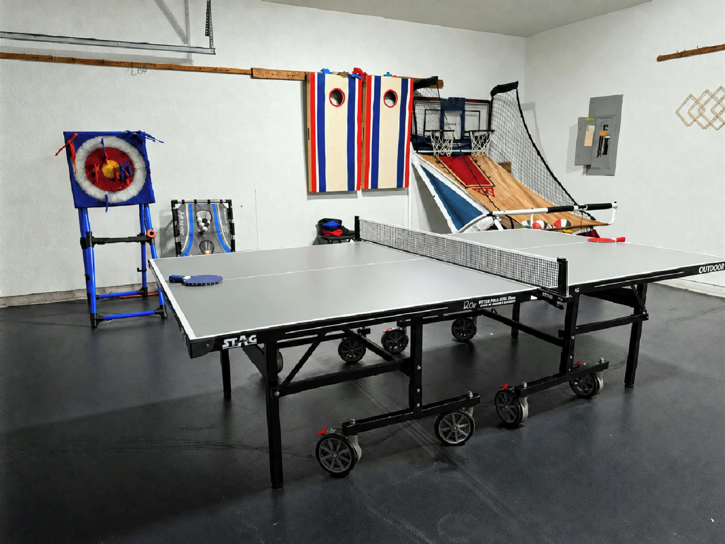 A ping pong table with wheels, a target with a ball, and a small basketball hoop.
