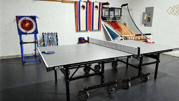 A ping pong table with wheels, a target with a ball, and a small basketball hoop.