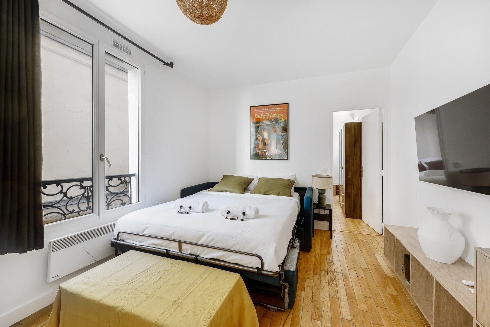 Ein Schlafzimmer mit Bett, Nachttisch, Lampe, Fernseher und einem Gemälde an der Wand.