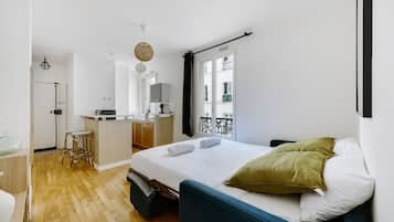 Una habitación de hotel compacta con cama, kitchenette pequeña y baño.