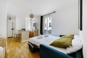 A compact hotel room with a bed, a small kitchenette, and a bathroom.