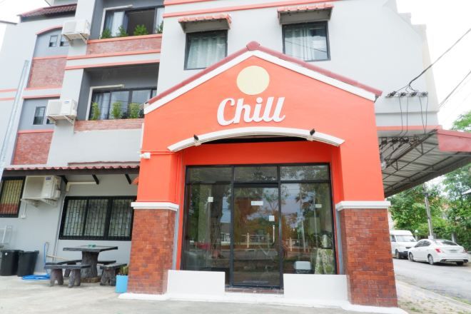 Un edificio con fachada roja y blanca, una amplia entrada de vidrio y un cartel que dice 'Chill'.