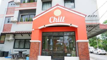 Un edificio con fachada roja y blanca, una amplia entrada de vidrio y un cartel que dice 'Chill'.