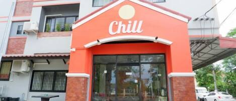 A building with a red and white facade, a large glass entrance, and a sign that reads 'Chill.'