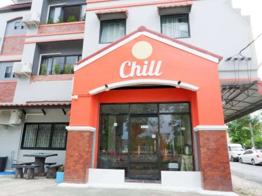 Ein Gebäude mit roter und weißer Fassade, einem großen Glaseingang und einem Schild mit der Aufschrift 'Chill'.
