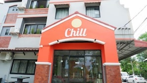 Un edificio con fachada roja y blanca, un amplio ventanal de vidrio y un letrero que dice 'Chill'.