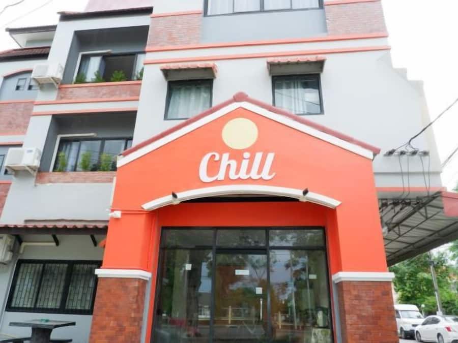 Un edificio con fachada roja y blanca, un amplio ventanal de vidrio y un letrero que dice 'Chill'.