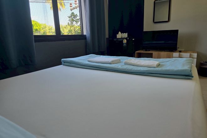 A hotel room with a bed, a television, a small table, and a window with curtains.