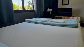 A hotel room with a bed, a television, a small table, and a window with curtains.