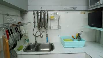 A kitchen with a double sink, stainless steel appliances, and a blue dish rack.