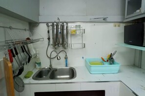 A kitchen with a double sink, stainless steel appliances, and a blue dish rack. - Chill @ Phetchaburi (Phetchaburi)