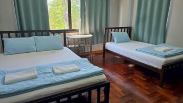 A room with two beds, a small table, and a window with curtains.