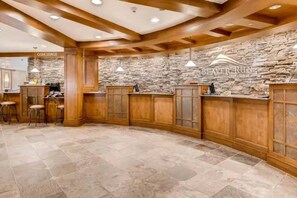 A bar area with stone walls, wooden bar counters, and bar stools.