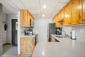 A kitchen with wooden cabinets, a stainless steel refrigerator, a microwave, and a coffee maker.