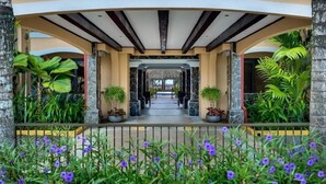 A covered walkway with potted plants and a stone wall in the background. - Resort style, ocean side, great location, WiFi, AC (Jacó)