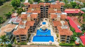 A multi-story hotel with a central swimming pool, surrounded by balconies and a red-roofed courtyard. - Resort style, ocean side, great location, WiFi, AC (Jacó)