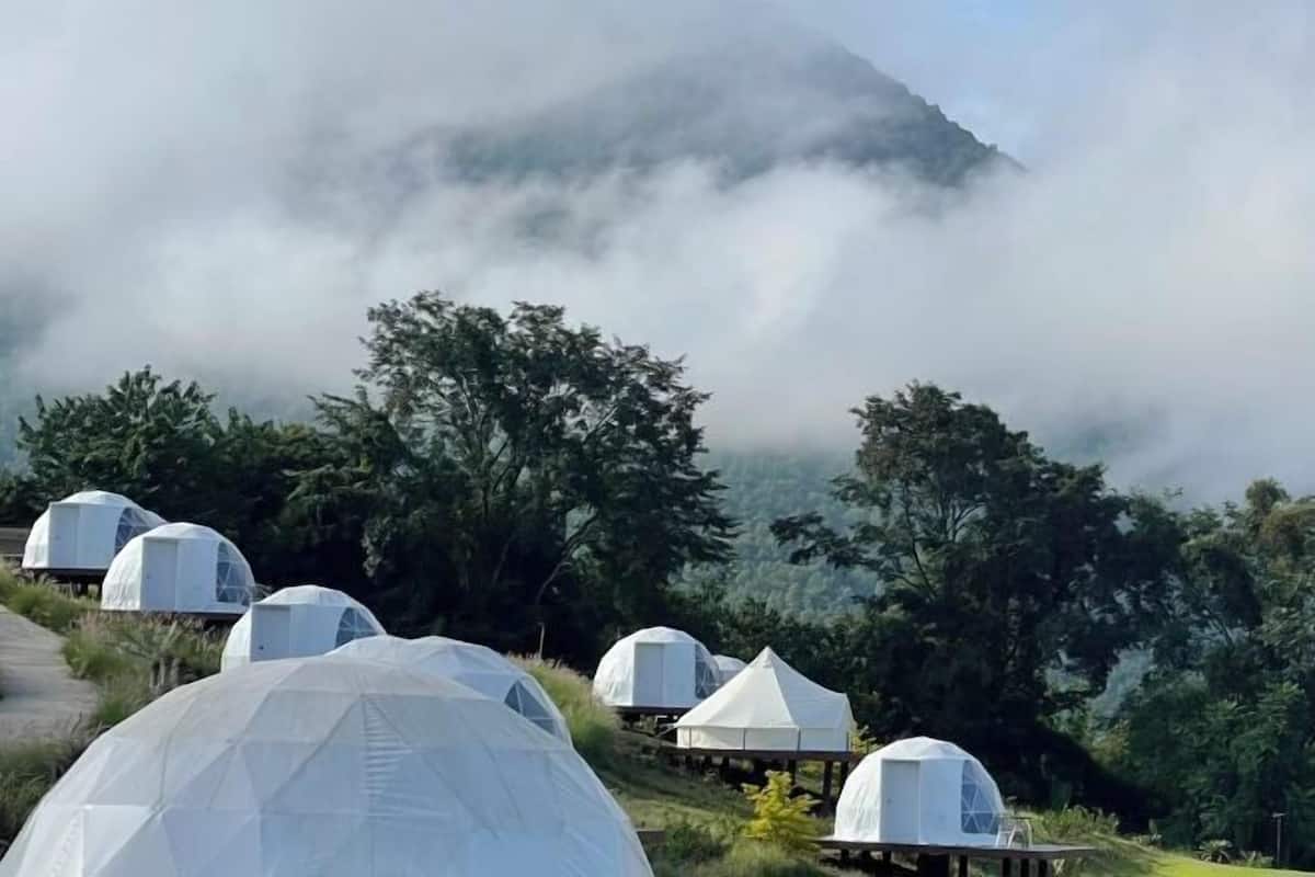 Dome-shaped accommodations in a natural setting with a mountainous backdrop.