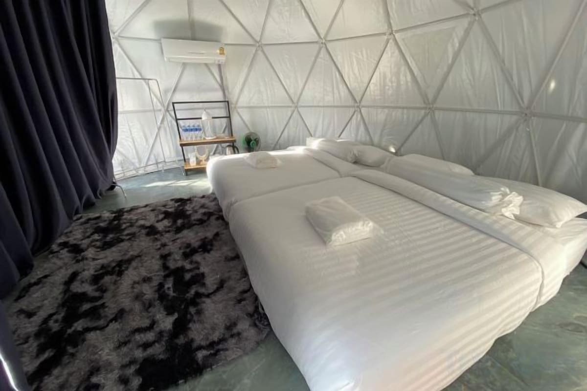 A room with a bed, a rug, and a wall-mounted air conditioning unit.