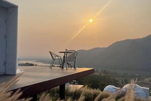An outdoor seating area with a table and chairs overlooking a scenic landscape.