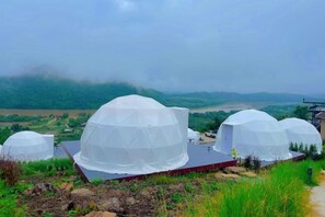 A series of dome-shaped structures with a flat roof, surrounded by greenery and a hilly landscape in the background. - Sky Bay Chiangkhan (Chiang Khan)