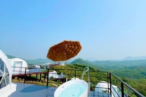 Un jacuzzi en un balcón con vistas a un paisaje montañoso.