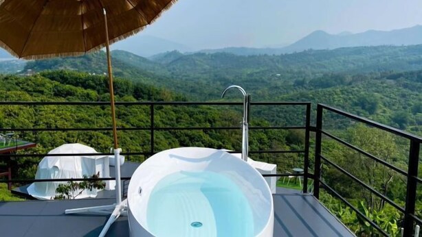 A hot tub on a balcony with a view of a lush green landscape. - Sky Bay Chiangkhan (Chiang Khan)