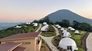 A series of dome-shaped accommodations with a central pathway, surrounded by lush greenery and a mountain in the background. - Sky Bay Chiangkhan (Chiang Khan)