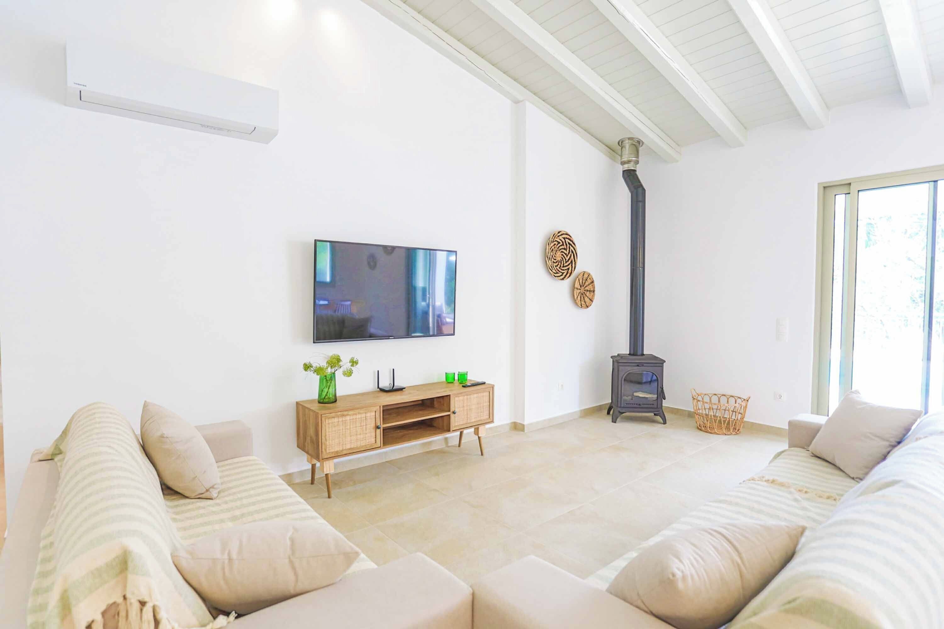 A modern living room with a flat-screen TV, a wooden entertainment unit, and a fireplace.