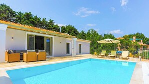 A modern poolside area with a clear pool, wicker furniture, and a covered seating area. - Villa Jupeter (Corfu)