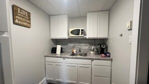 A compact kitchen with white cabinets, a microwave, a toaster, and a coffee maker.