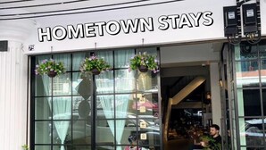 Une devanture de magasin avec une enseigne indiquant « HOMETOWN STAYS » et un panneau à l’extérieur annonçant « OUVERT MAINTENANT ».