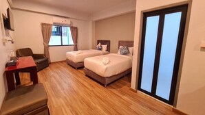 Une chambre d’hôtel avec deux lits, un bureau, une chaise et une fenêtre avec des rideaux.