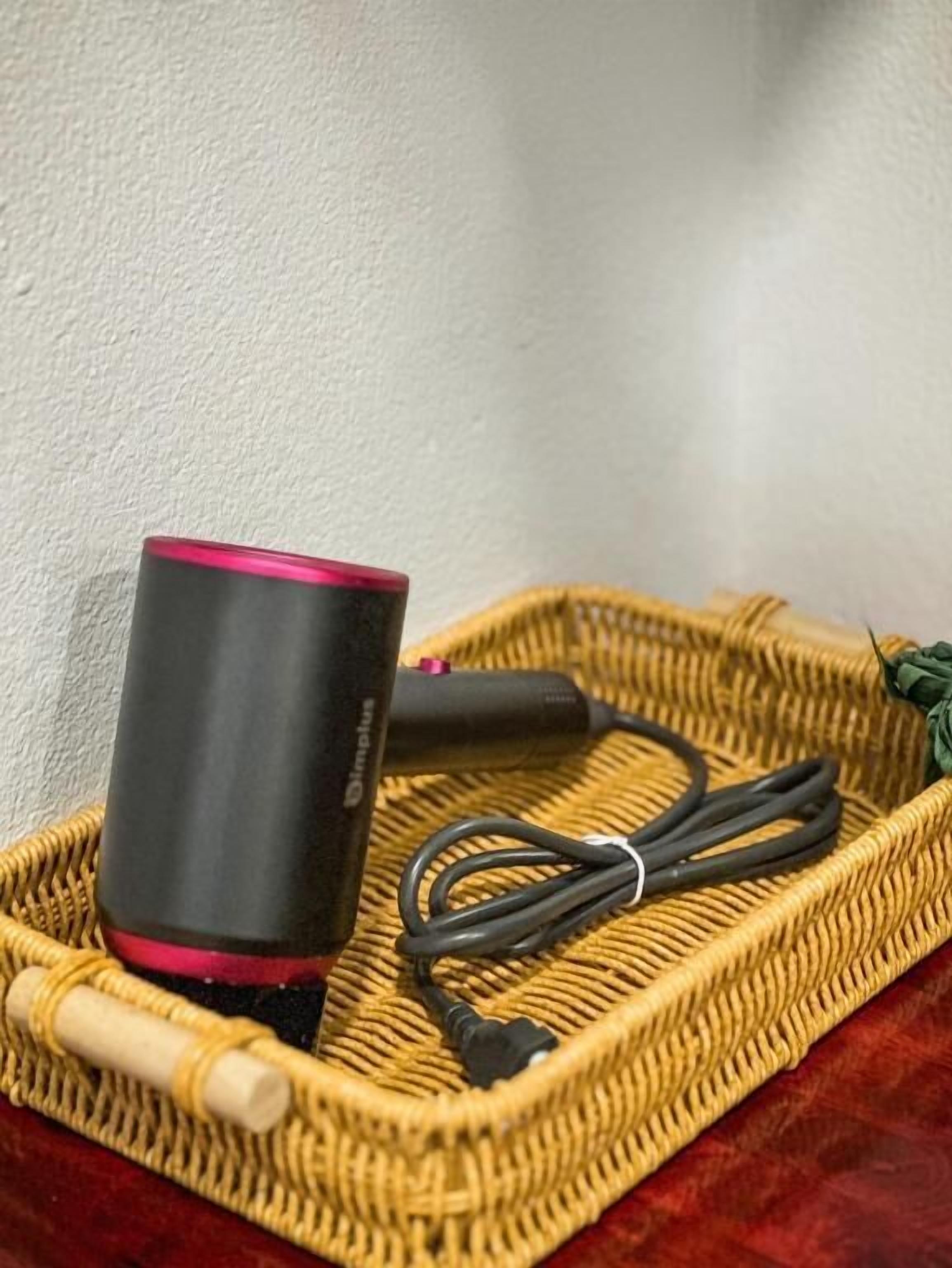 Une tasse noire à bord rouge, posée sur un plateau tressé.